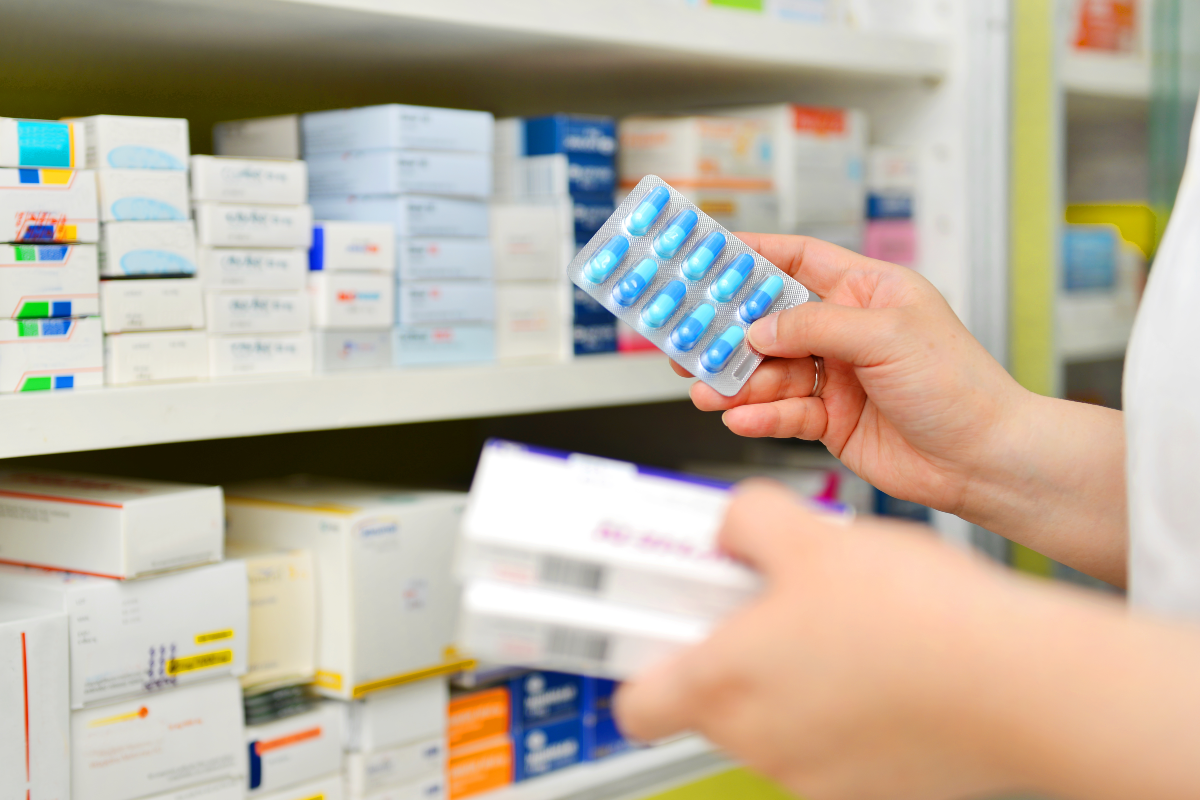 Un pharmacien tenant une boîte à médicaments et une capsule dans une pharmacie