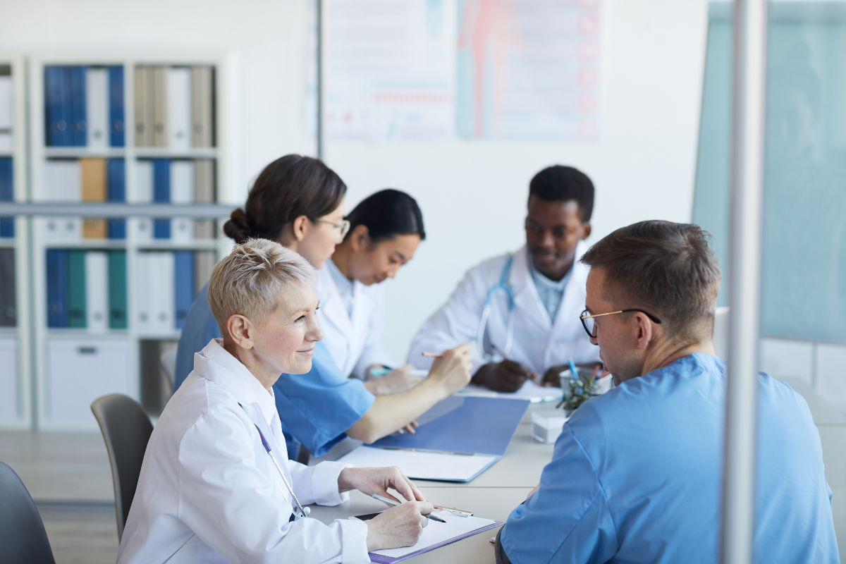 Groupe de médecins assis à la table ronde pendant le conseil médical